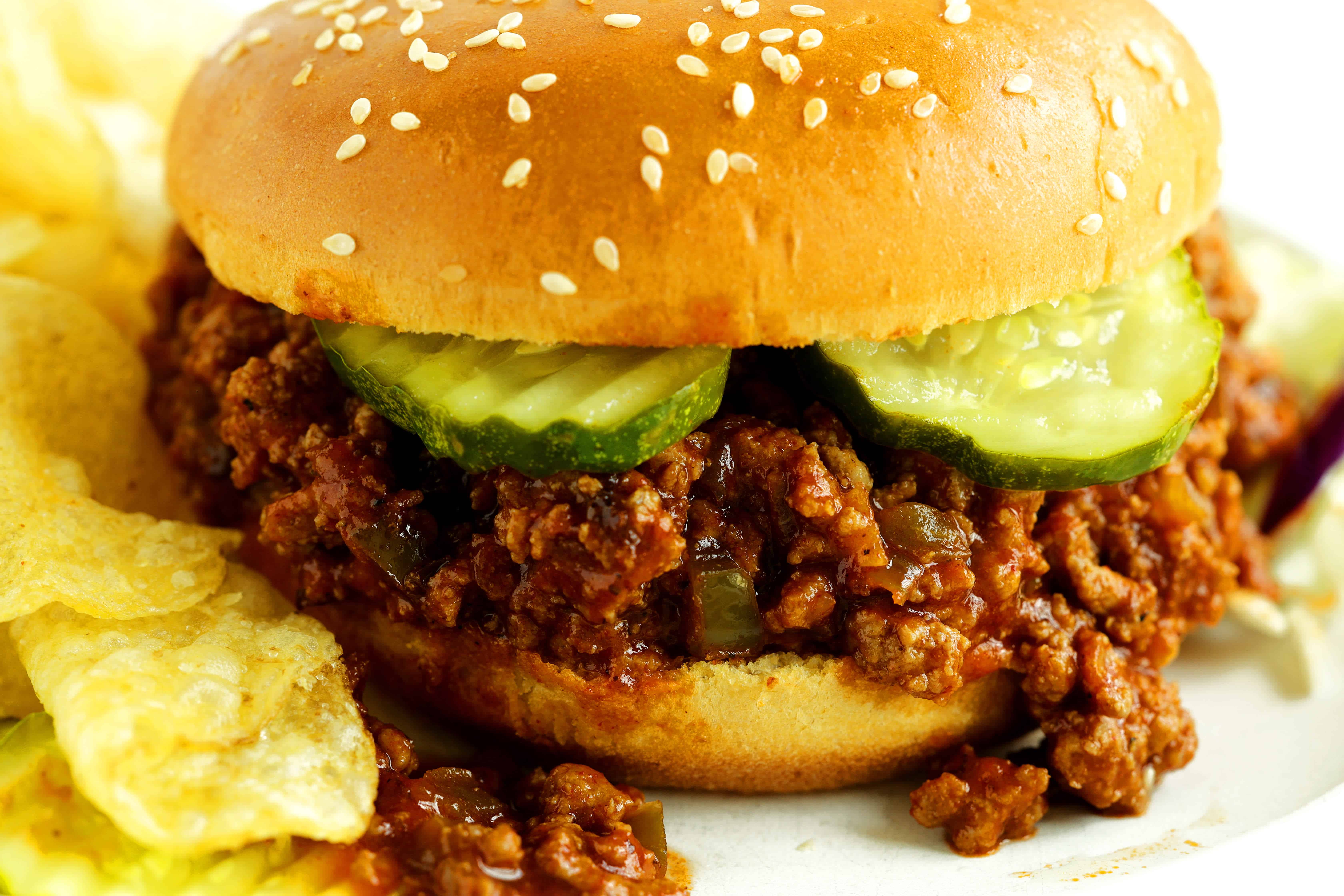 Closeup of Turkey Sloppy Joe with potato chips and sliced pickles