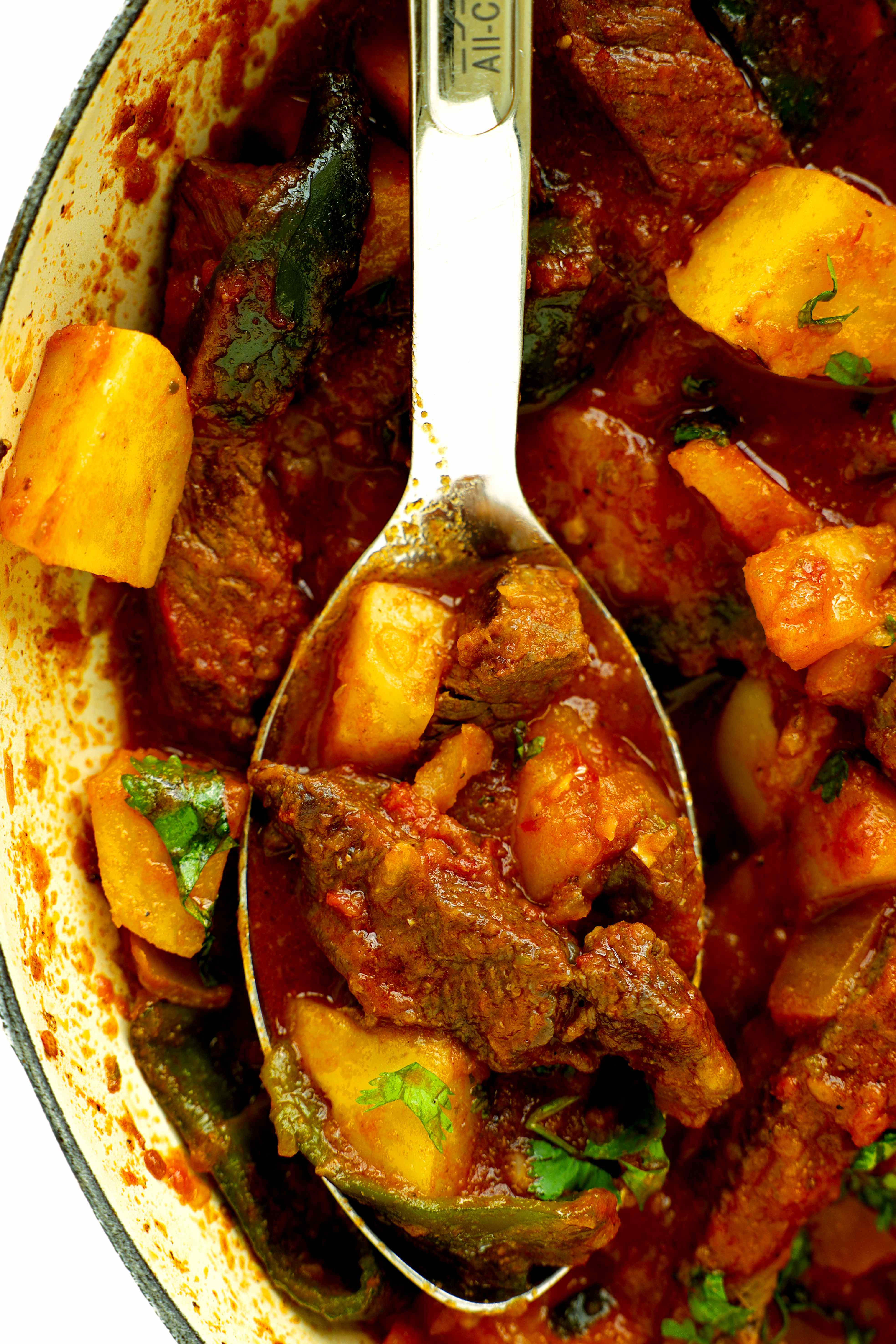 Closeup of Bistec Ranchero in a Dutch oven with a serving spoon