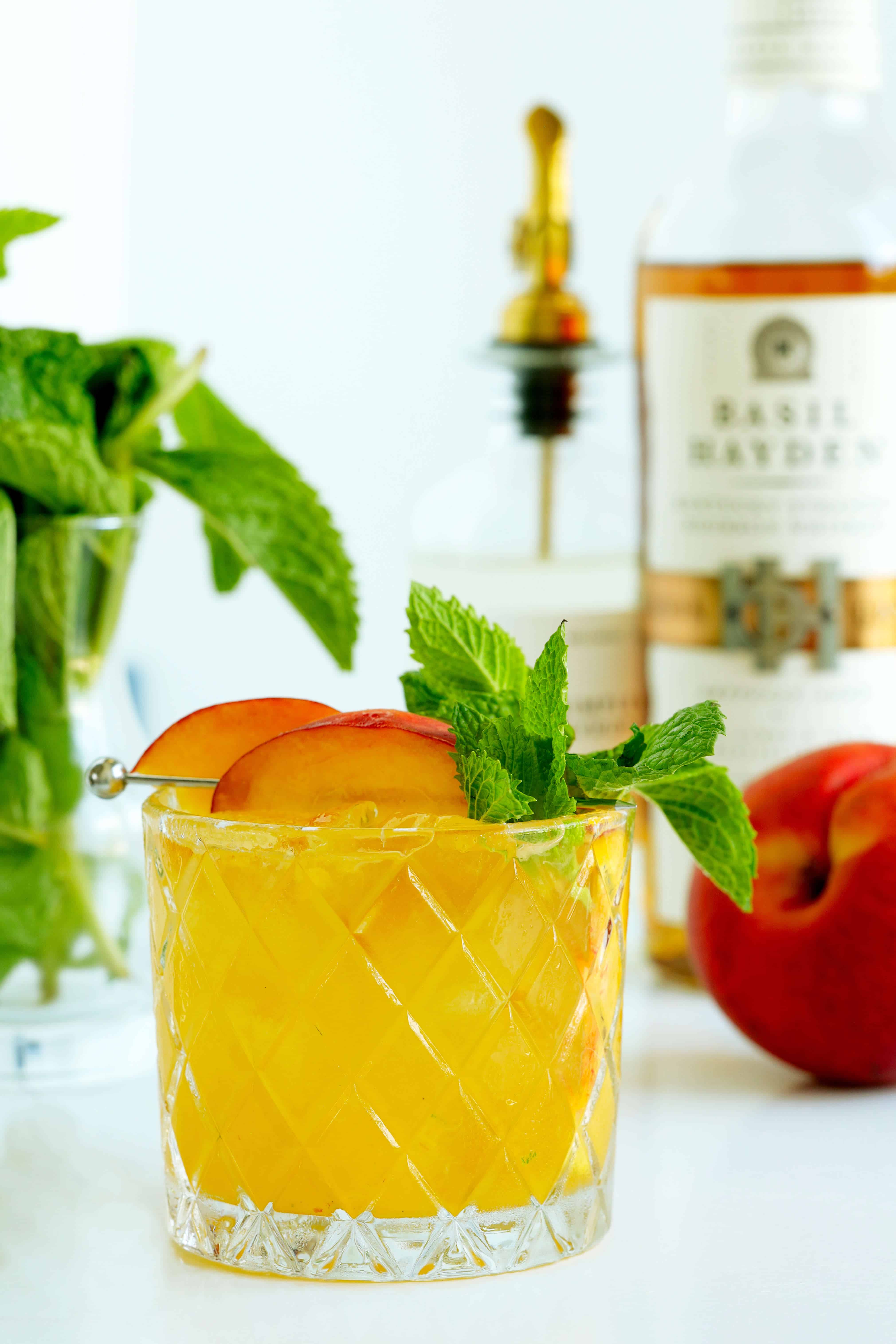 Peach Bourbon Smash cocktail garnished with peach slices and fresh mint