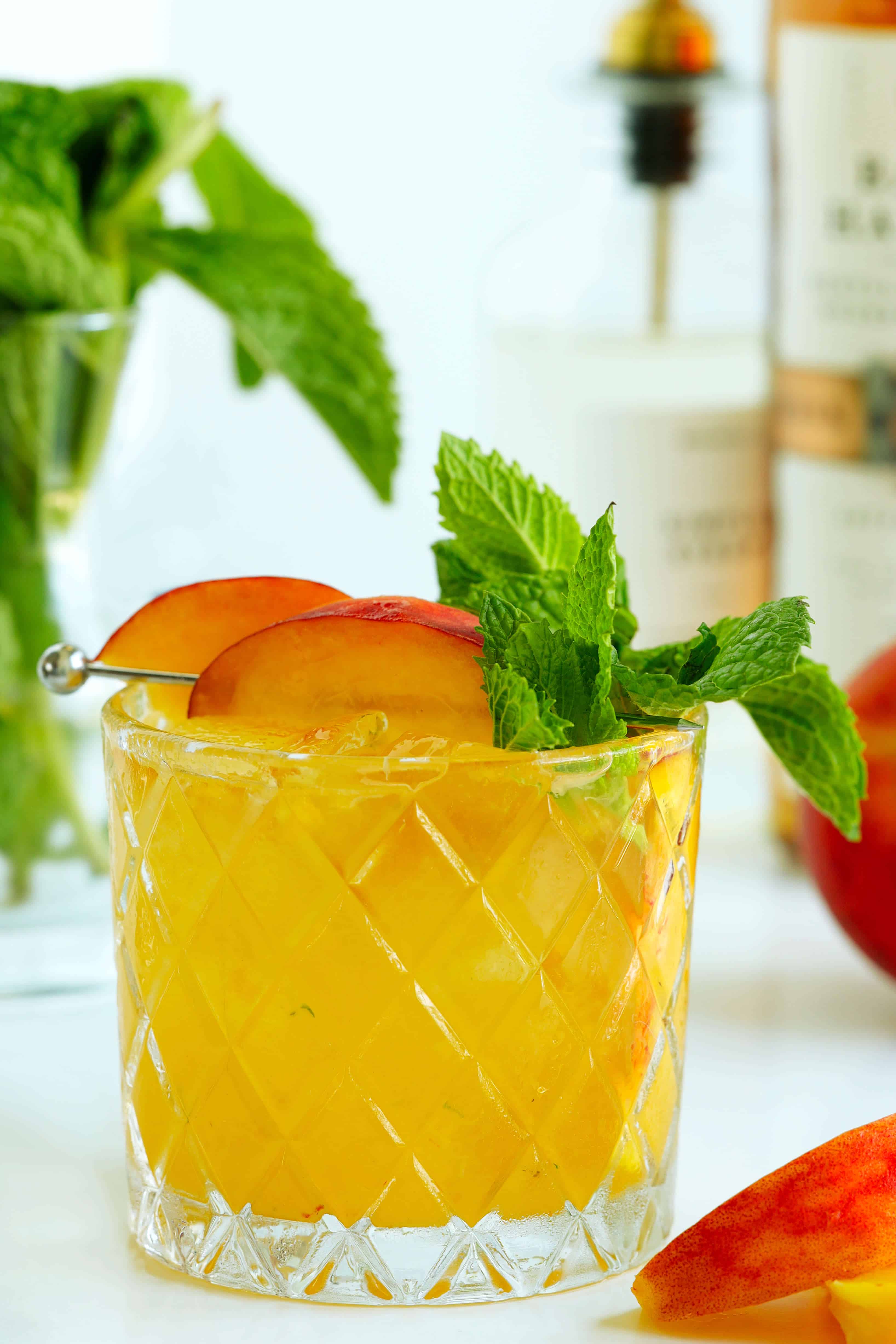 Peach Bourbon Smash cocktail garnished with peach slices and fresh mint
