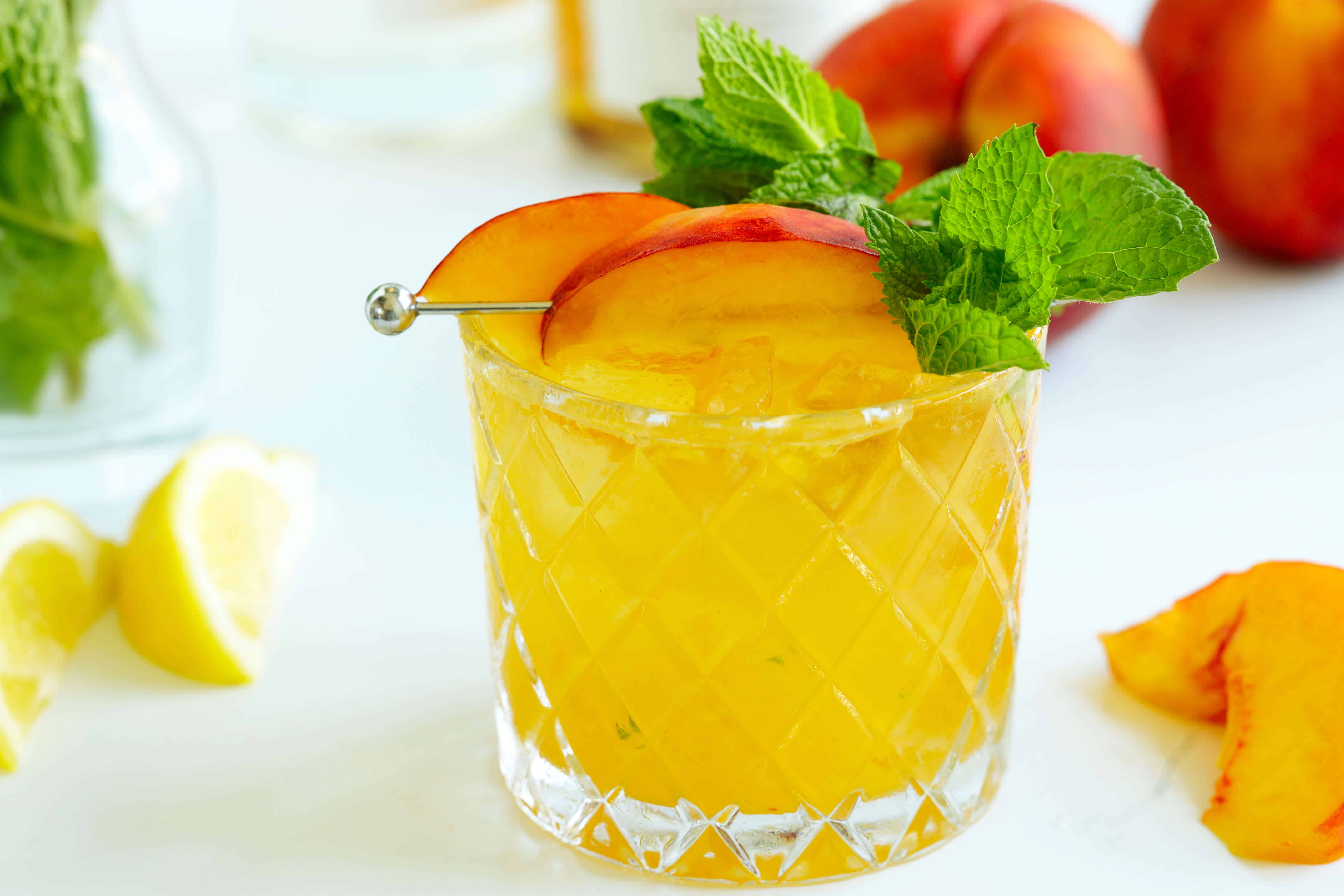 Peach Bourbon Smash cocktail garnished with peach slices and fresh mint