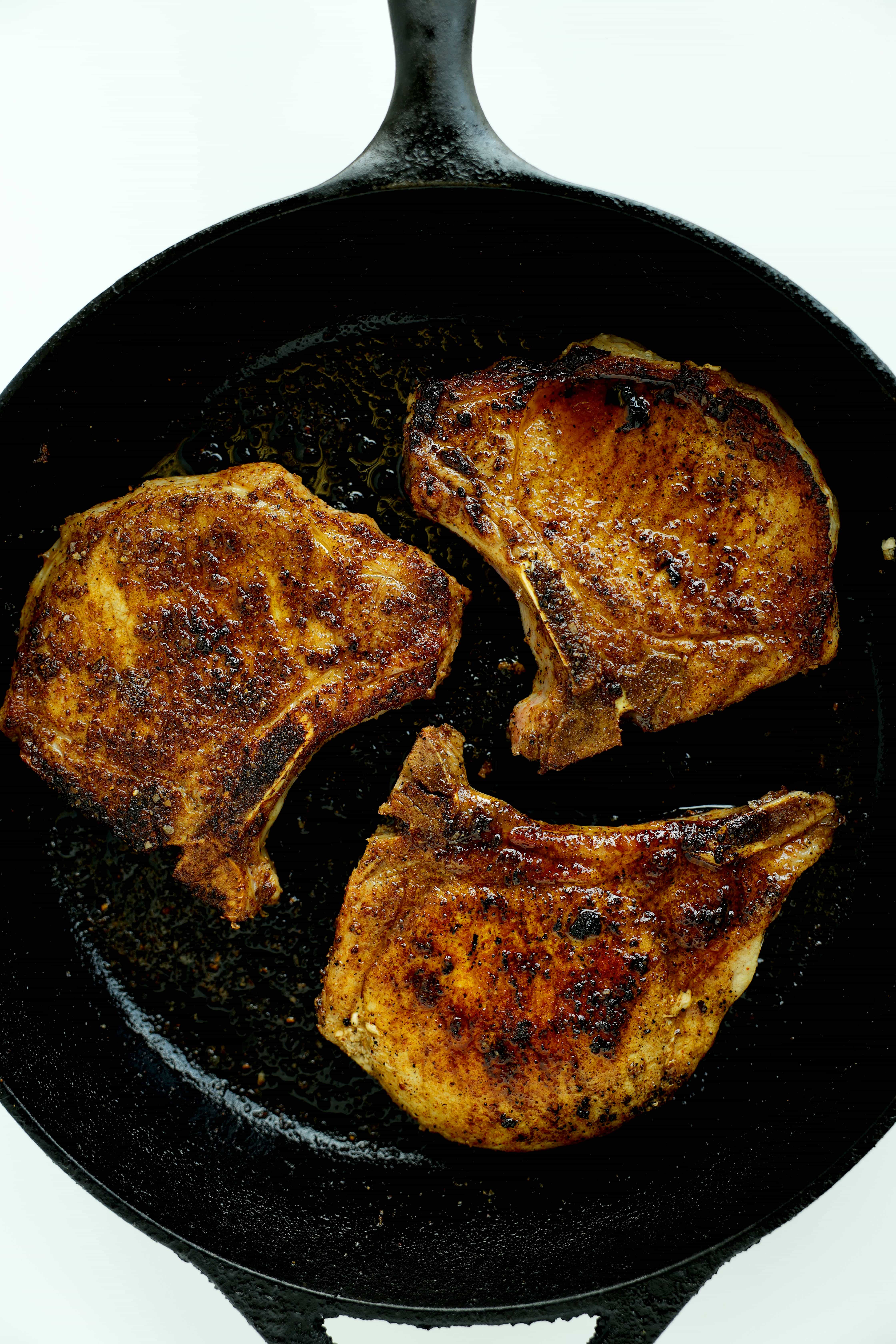 Pork Chops seasoned with Pork Chop Seasoning in a cast-iron skillet
