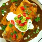 Overhead shot of Wet Burrito topped with guacamole, sour cream, diced tomatoes, and cilantro