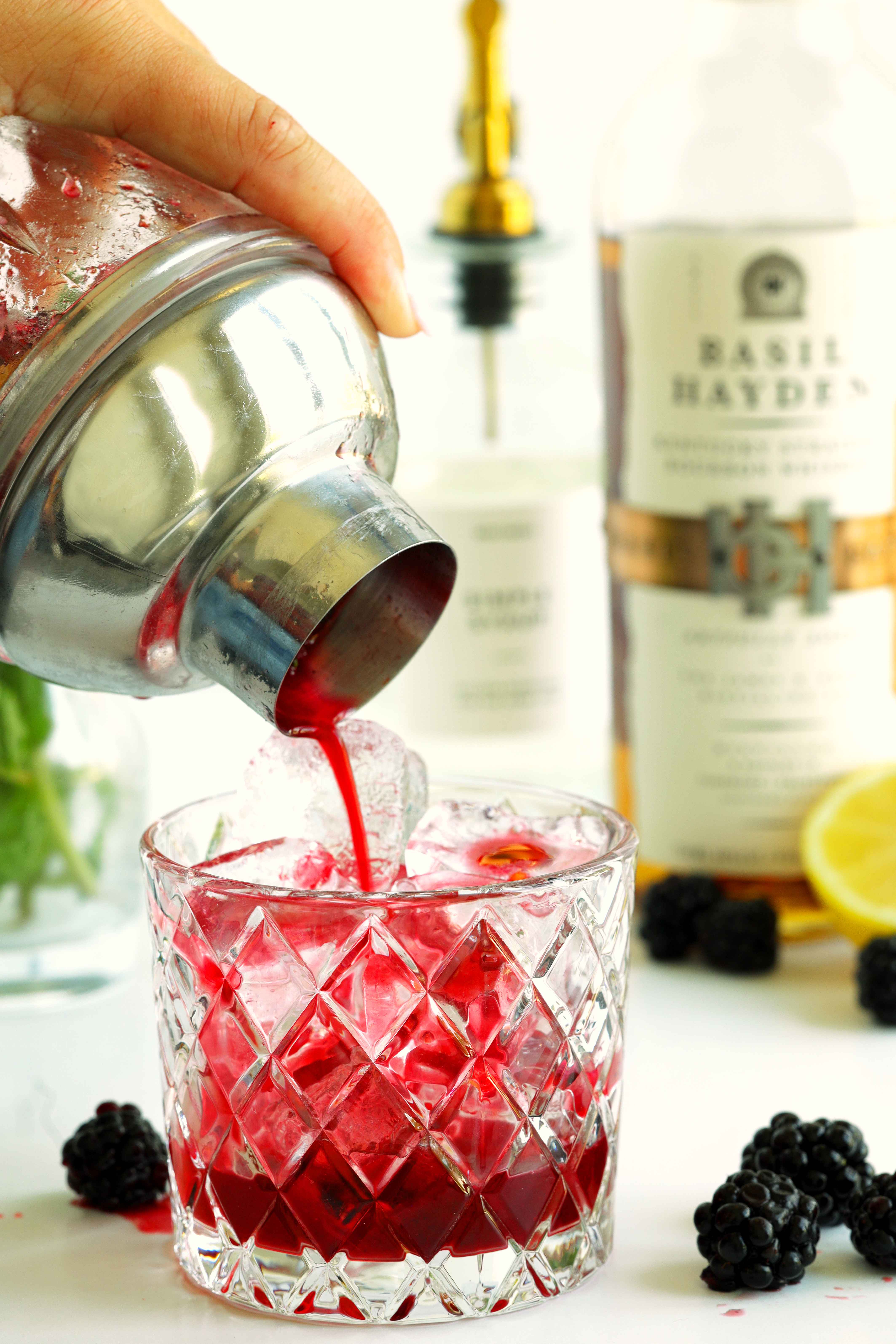 Pouring the Blackberry Bourbon Smash from a shaker into a rock glass