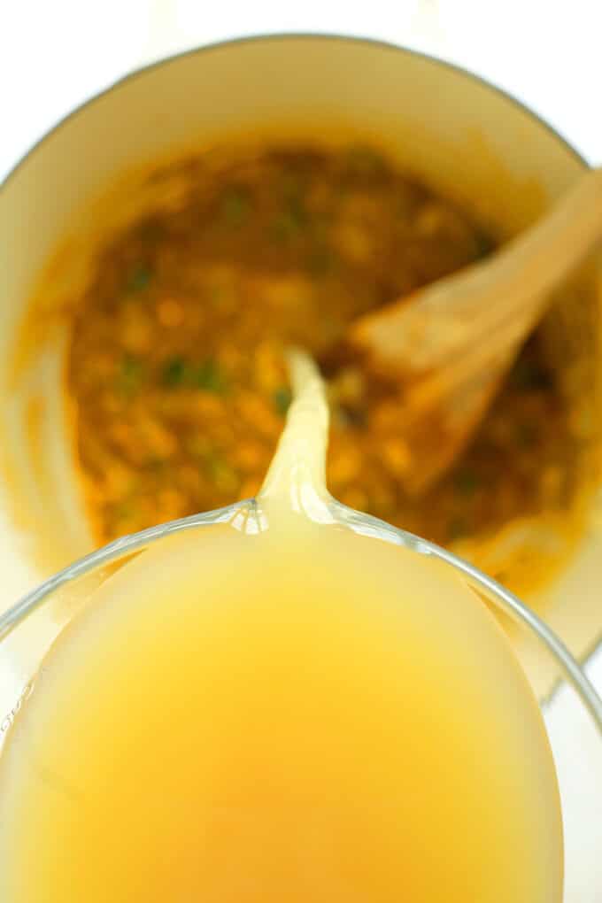 Pouring bone broth in Chicken Enchilada soup prep
