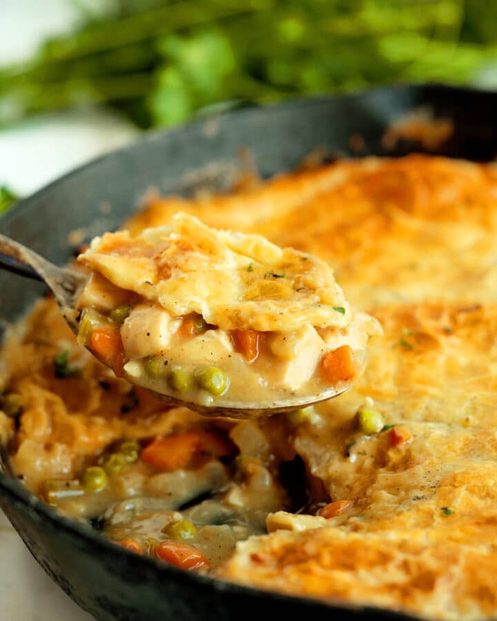 Close-up shot of Chicken Pot Pie with Puff Pastry with a spoon in a cast iron skillet