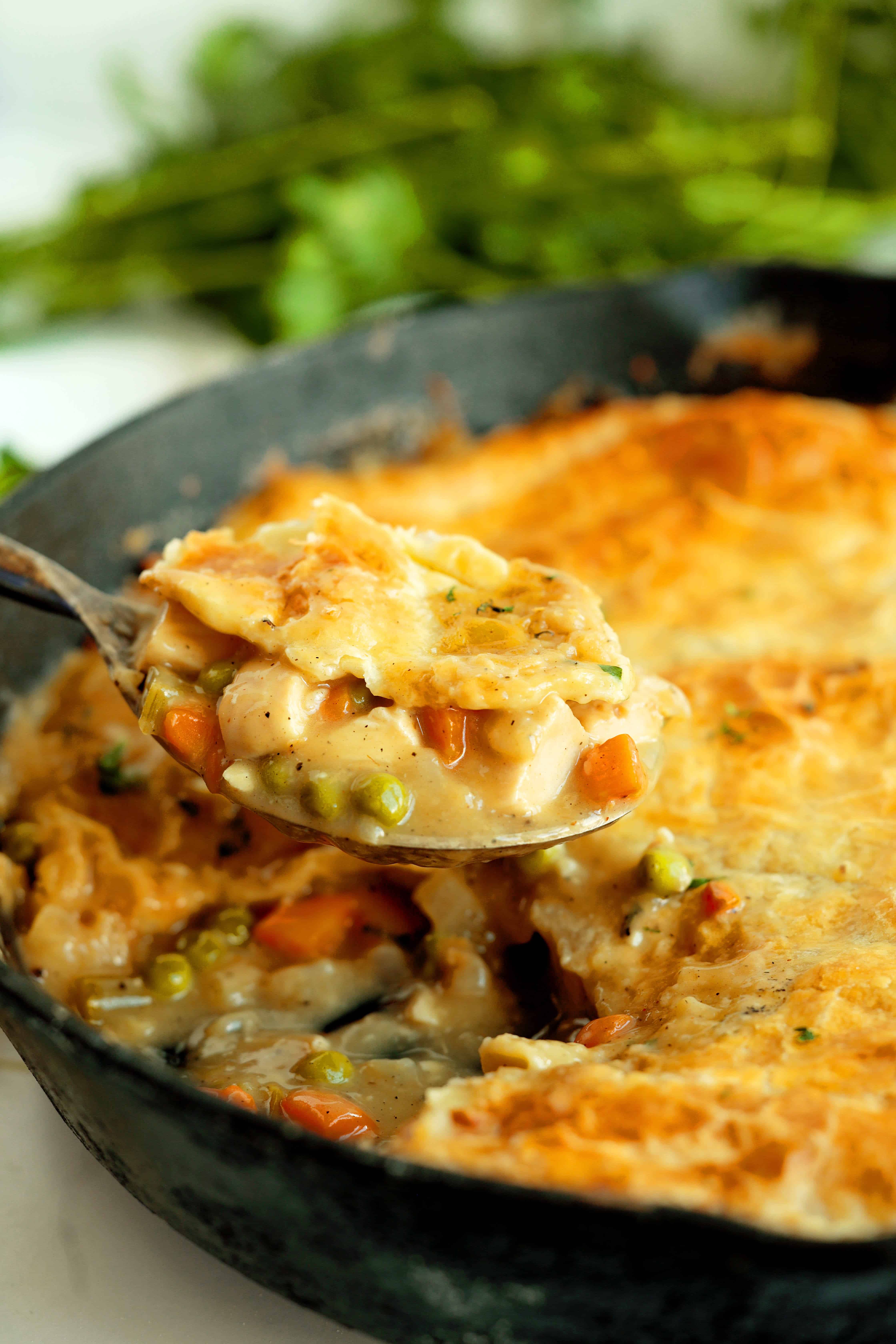 Close-up shot of Chicken Pot Pie with Puff Pastry with a spoon in a cast iron skillet