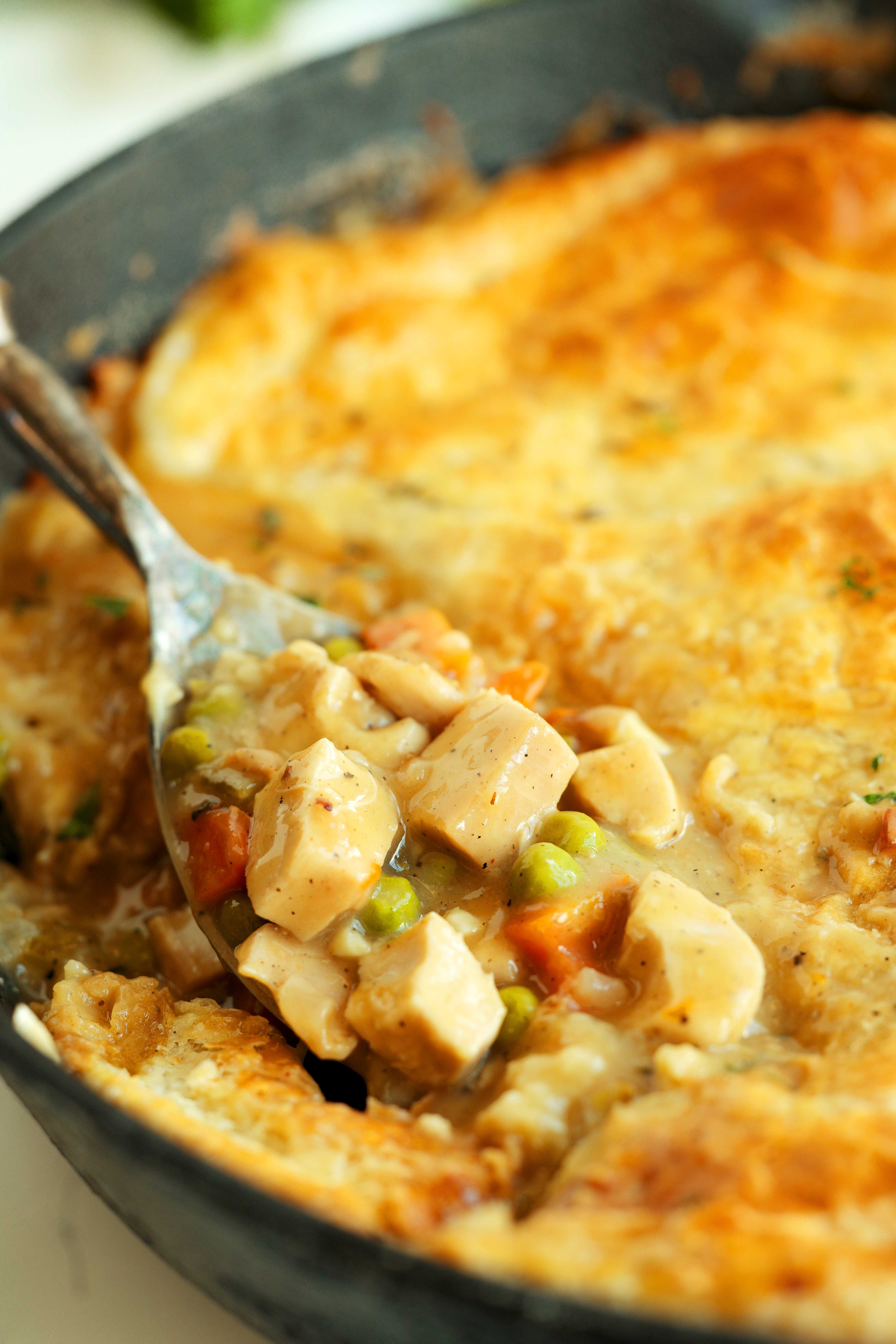 Close-up shot of Chicken Pot Pie with Puff Pastry with a spoon in a cast iron skillet