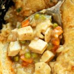 Overhead, close-up shot of Chicken Pot Pie with Puff Pastry with a spoon in a cast iron skillet