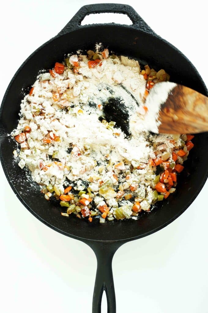 Adding flour to sauteed veggies for Chicken Pot Pie with Puff Pastry in a cast iron skillet