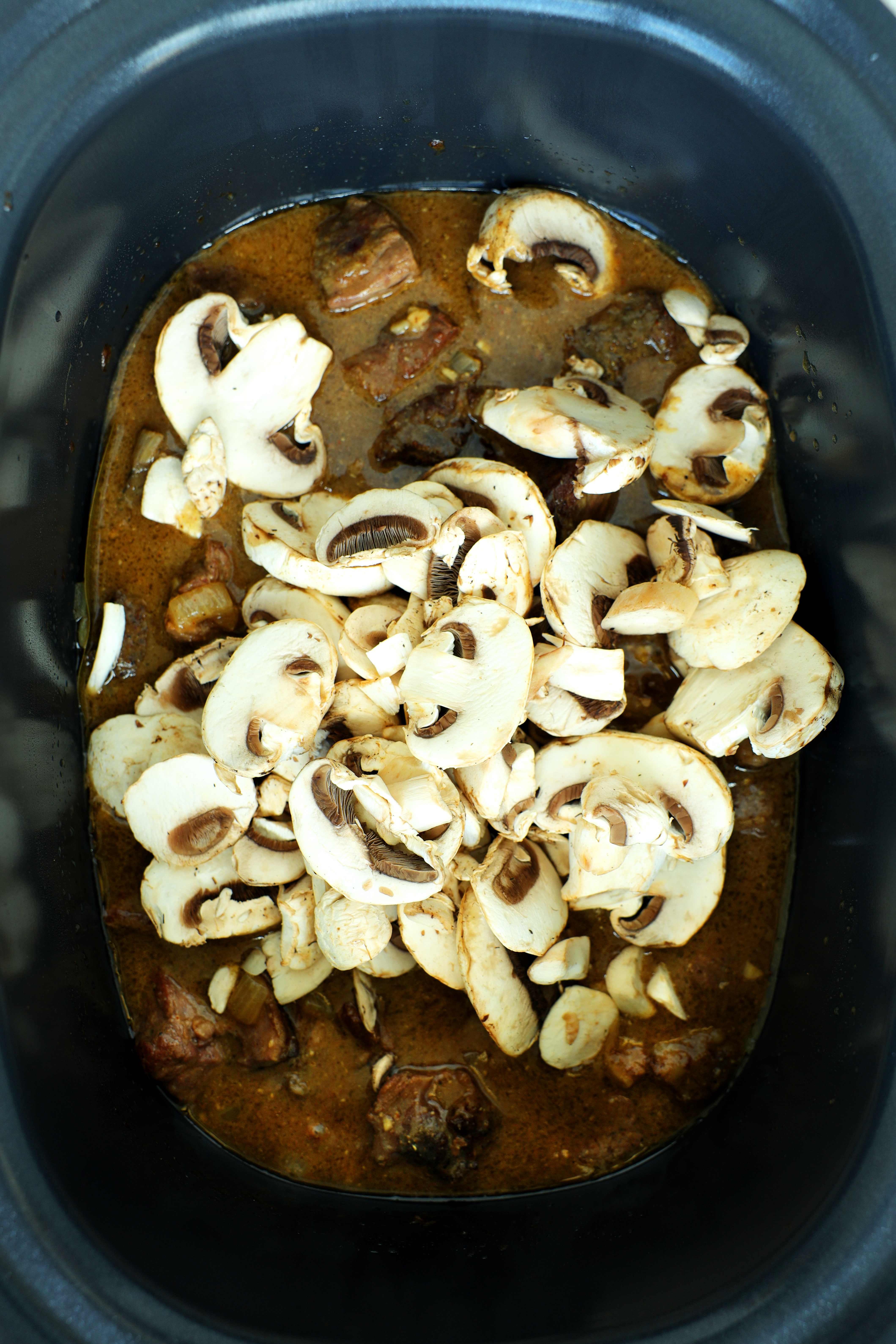 Adding mushrooms to the crockpot for beef tips and gravy