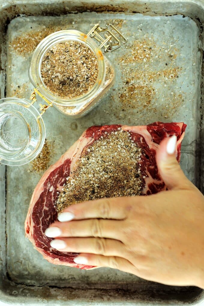 Patting homemade steak seasoning onto a steak