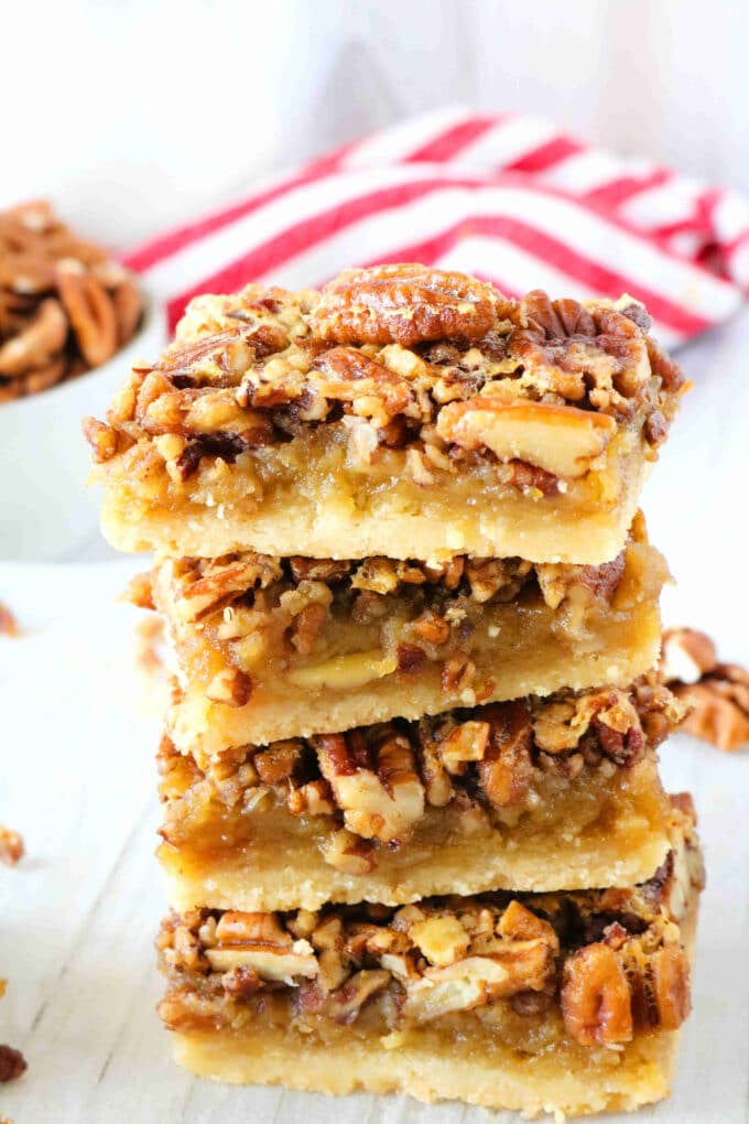 Stack of pecan pie bars with glossy pecan topping on a buttery shortbread crust.