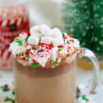 Christmas hot chocolate in a glass mug with whipped cream and crushed candy canes.