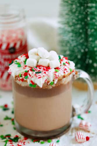 Christmas hot chocolate in a glass mug with whipped cream and crushed candy canes.