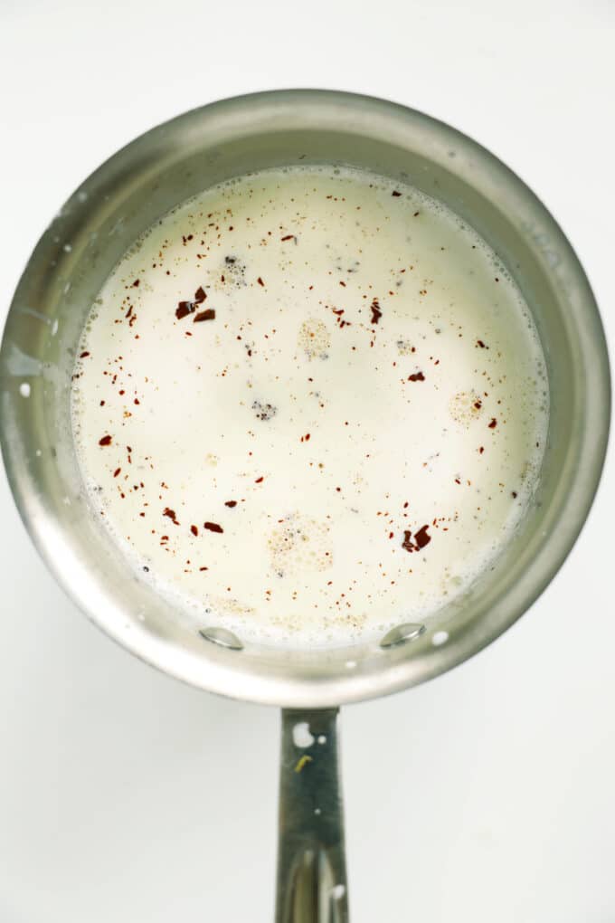 Chocolate flecks melting in hot milk in a saucepan&mdash;the beginning of dark hot chocolate.