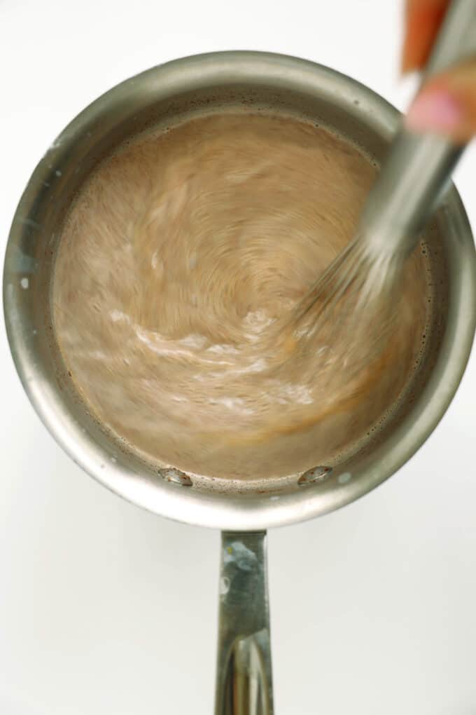 Whisking hot chocolate in a saucepan until smooth and steamy.