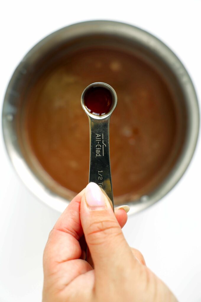 Vanilla extract held over a saucepan of hot chocolate.