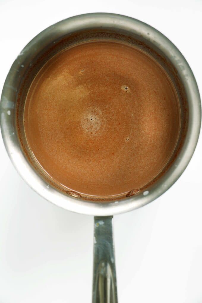 Smooth cocoa mixture simmering in a saucepan&mdash;rich dark hot chocolate base.