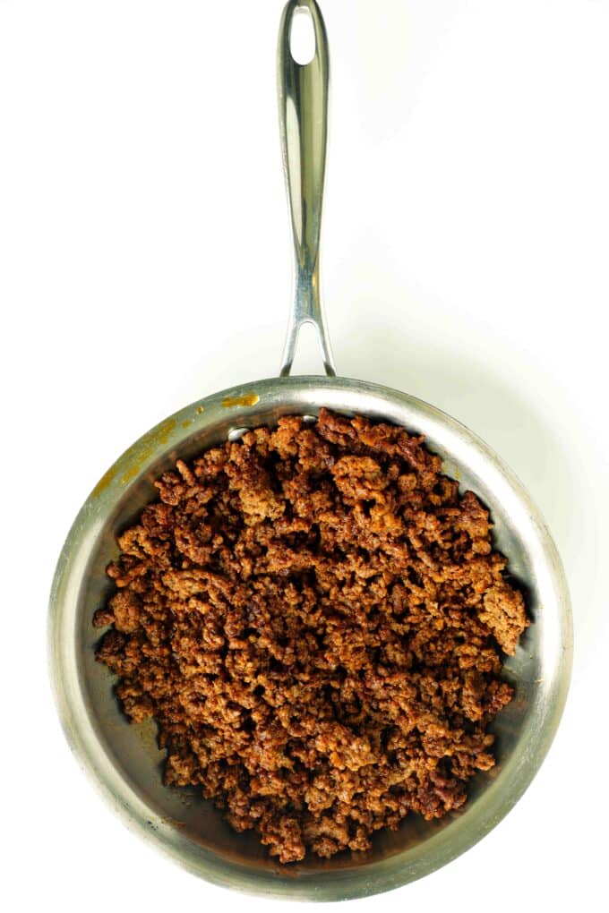 Seasoned ground beef taco meat cooked in skillet for a beef taco bowl