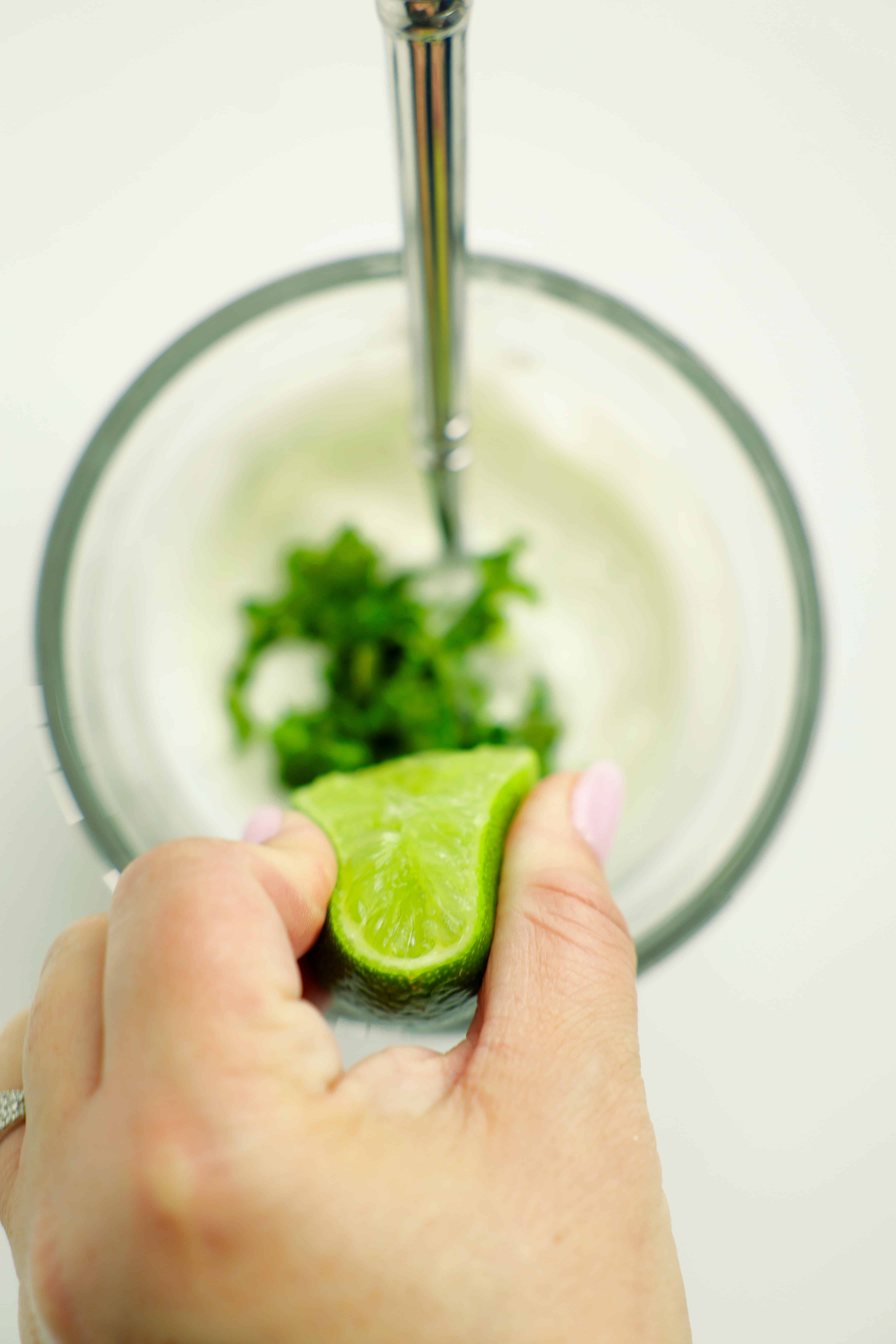 Squeezing lime into Greek yogurt cilantro sauce for taco bowls