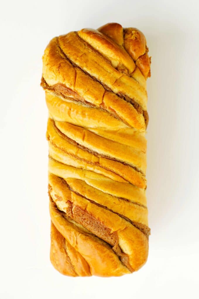 Whole brioche loaf with a golden crust on a white background.