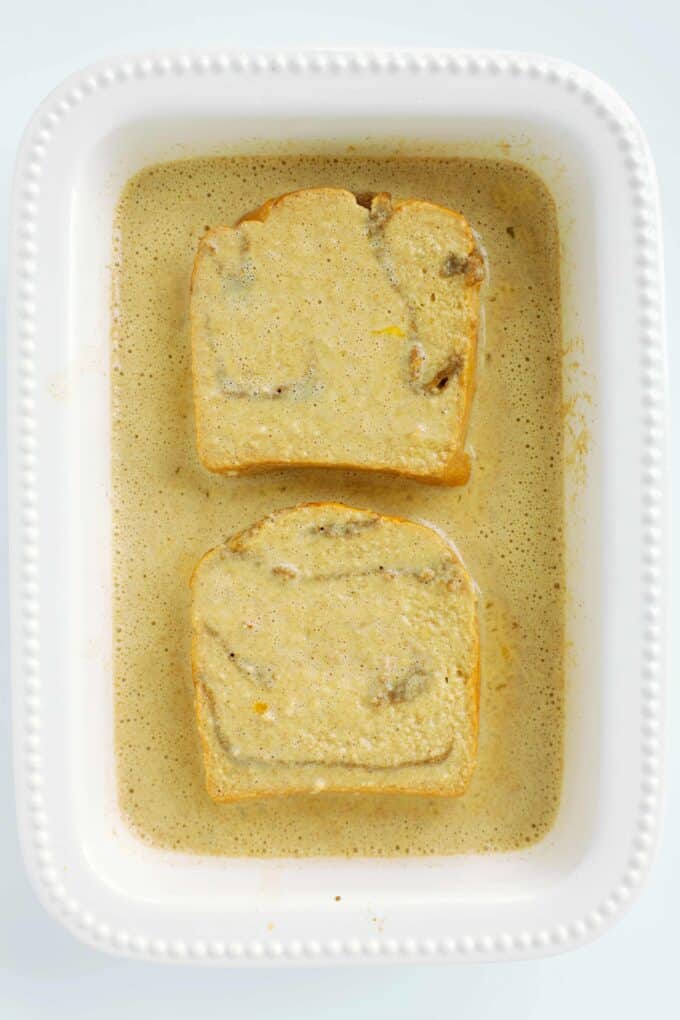 Thick slices of brioche bread soaking briefly in a cinnamon-spiced egg custard.