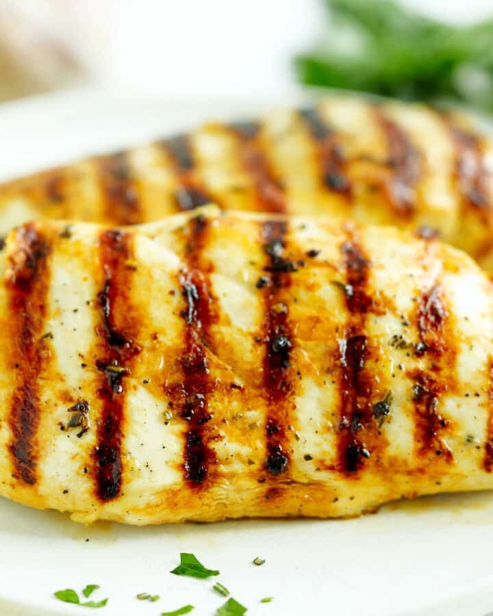 Close-up of grilled chicken breast with charred grill marks and garlic herb marinade