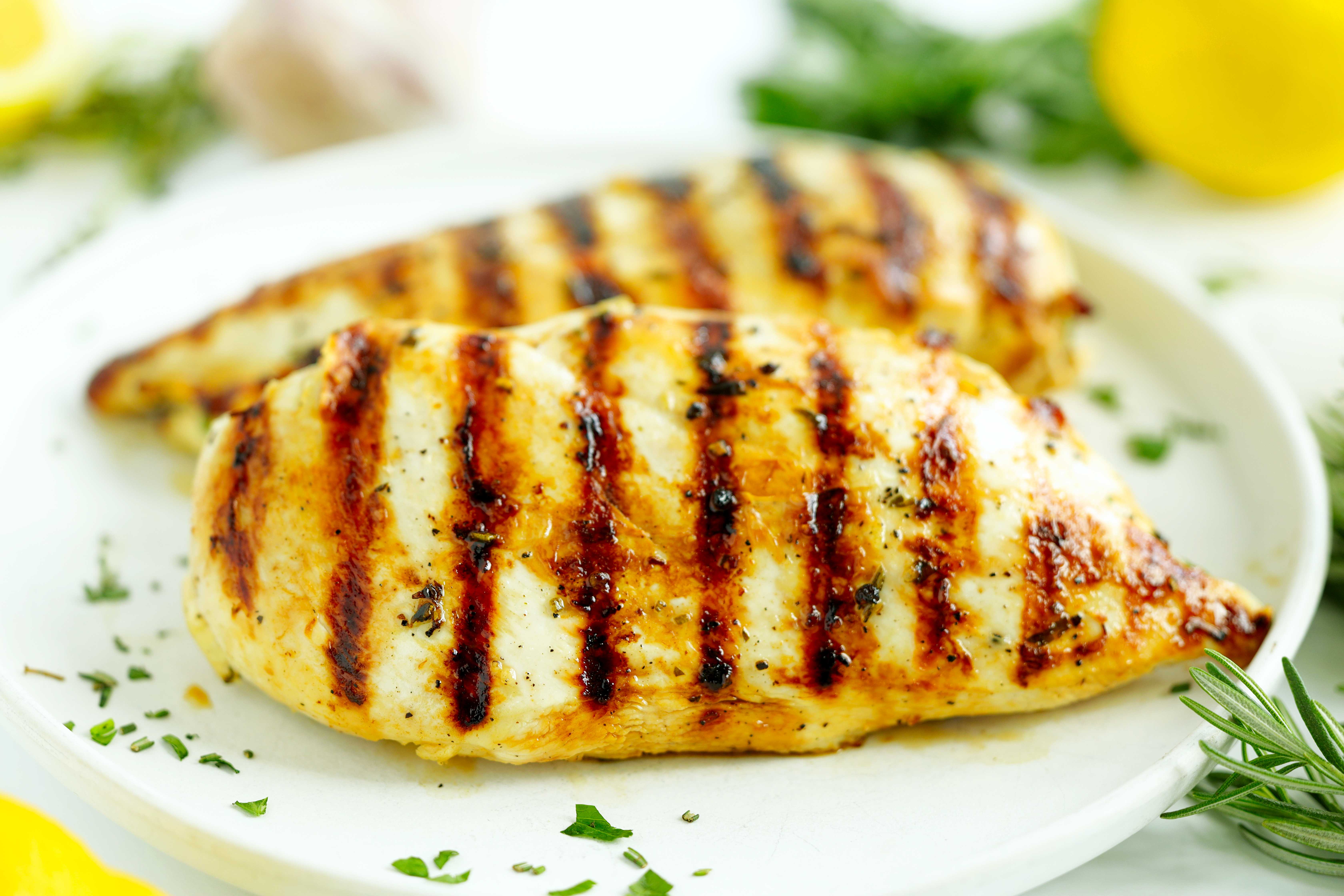 Close-up of grilled chicken breast with charred grill marks and garlic herb marinade
