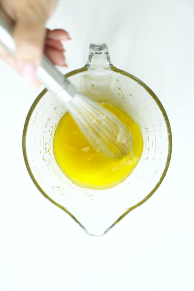 Whisking olive oil and lemon juice together to start a simple chicken marinade
