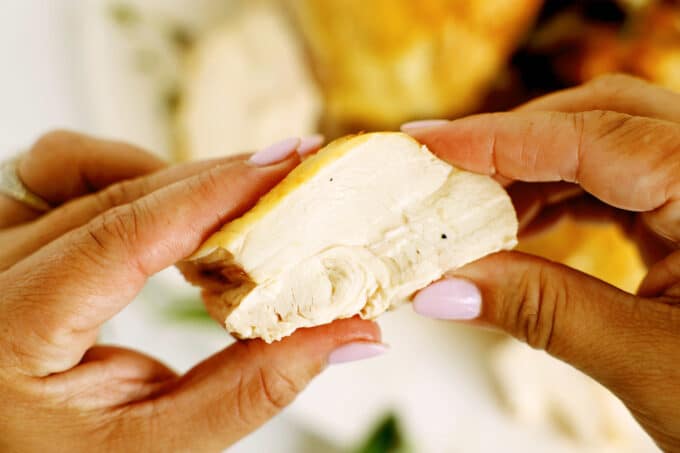 Holding sliced chicken breast to show tender, juicy interior