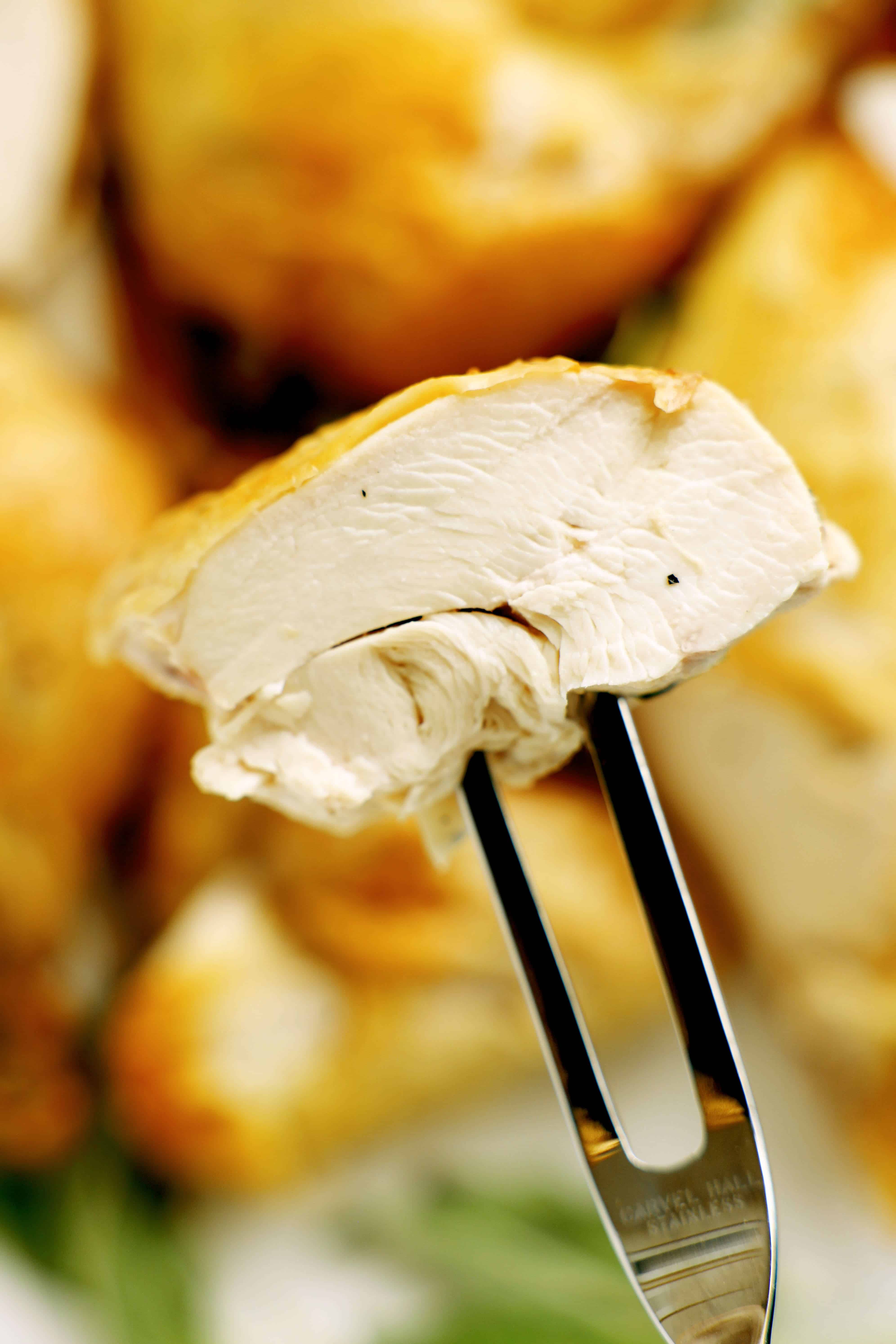 Close-up of cooked chicken breast on fork showing moist texture
