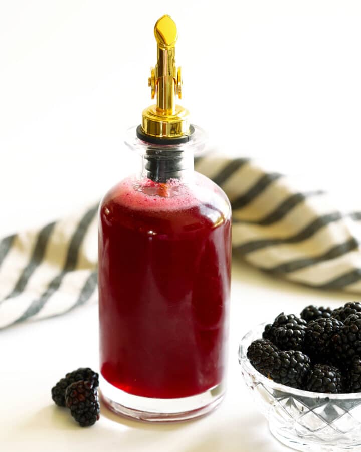 Bottle of homemade blackberry simple syrup with fresh blackberries