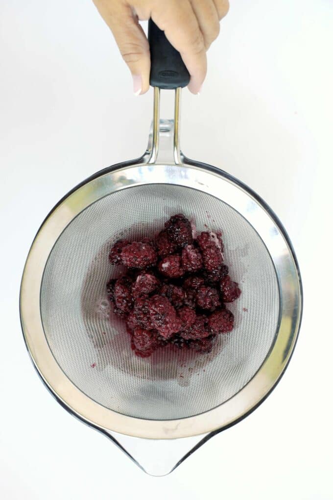 Straining cooked blackberries to separate the syrup from the pulp