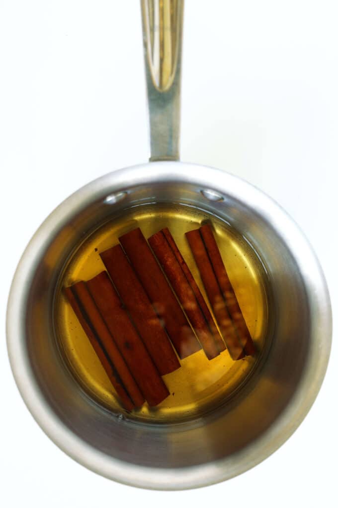 Cinnamon sticks steeping in hot water in a saucepan for homemade cinnamon syrup.