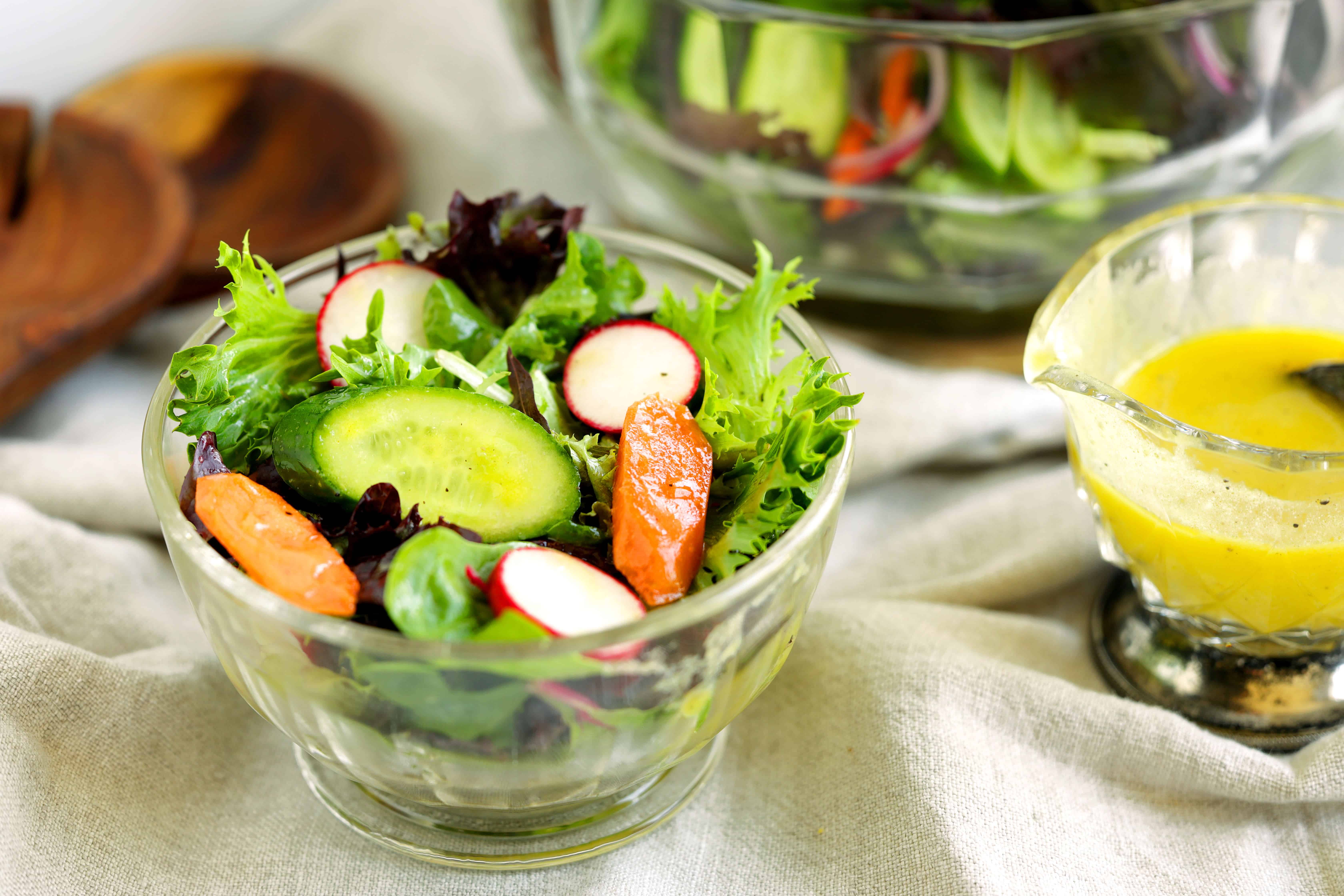 Fresh mixed green salad with cucumbers, radishes, and carrots served with Dijon dressing