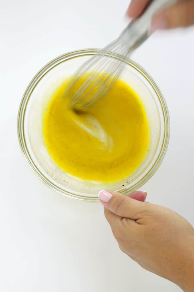 Whisking homemade Dijon dressing until smooth and emulsified