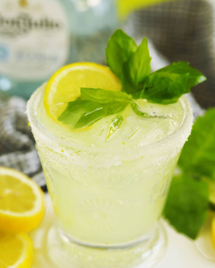 Close-up limoncello margarita with ice, lemon, basil, and a sugar rim