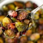 Overhead view of roasted Brussels sprouts with bacon and balsamic glaze in a white serving bowl