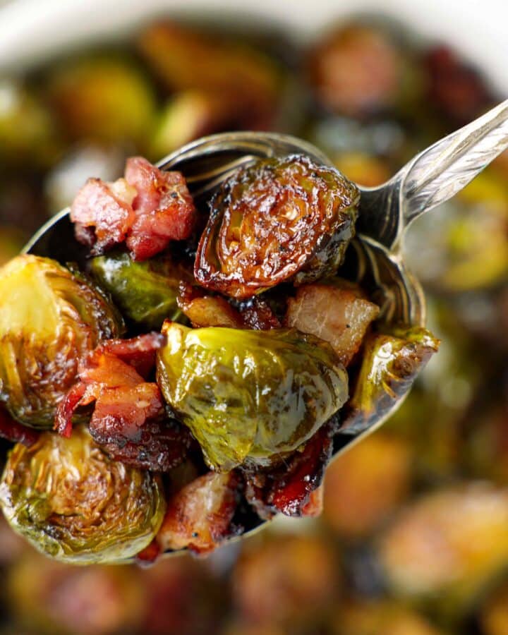 Overhead view of roasted Brussels sprouts with bacon and balsamic glaze in a white serving bowl