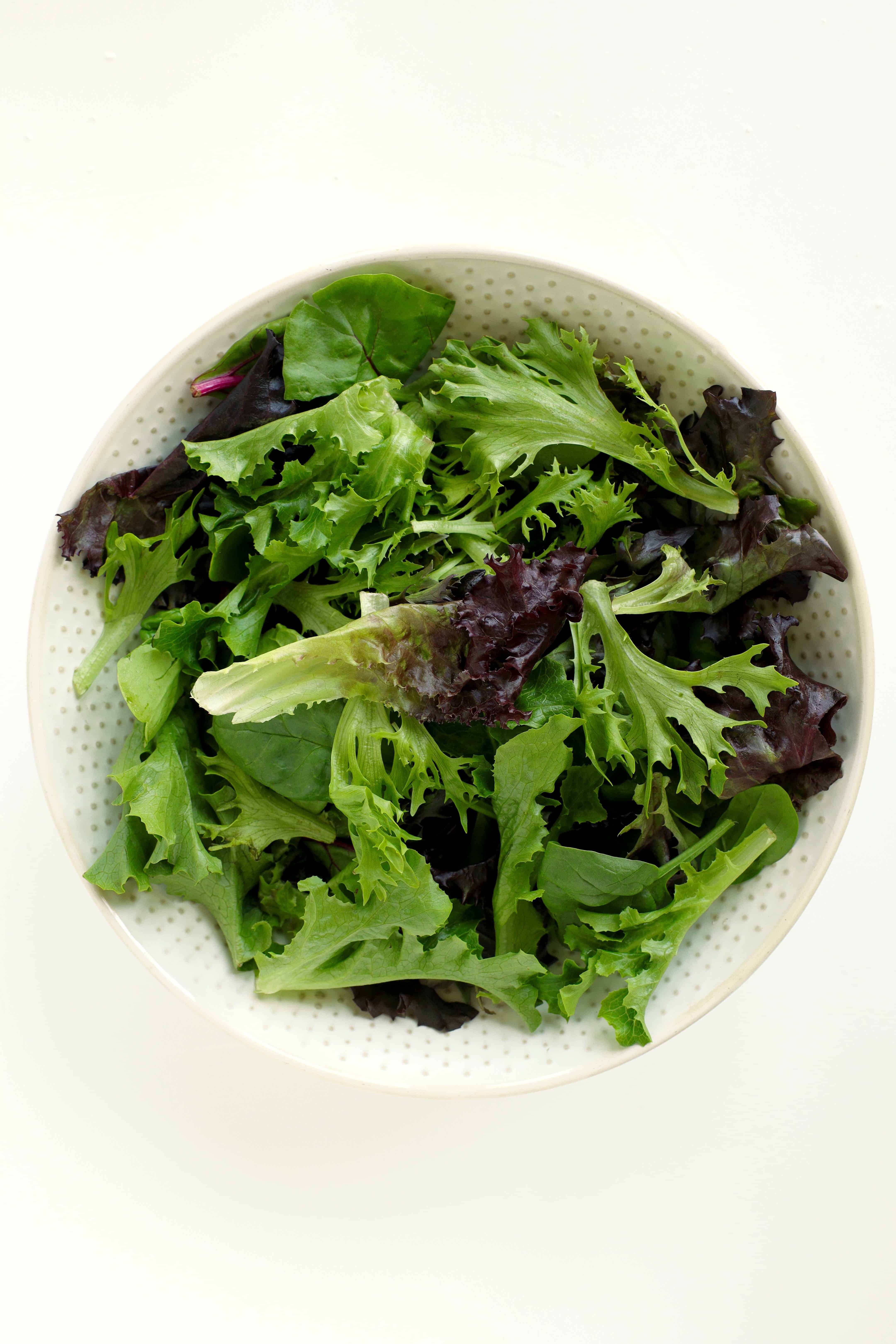 Spring mix greens in a white salad bowl
