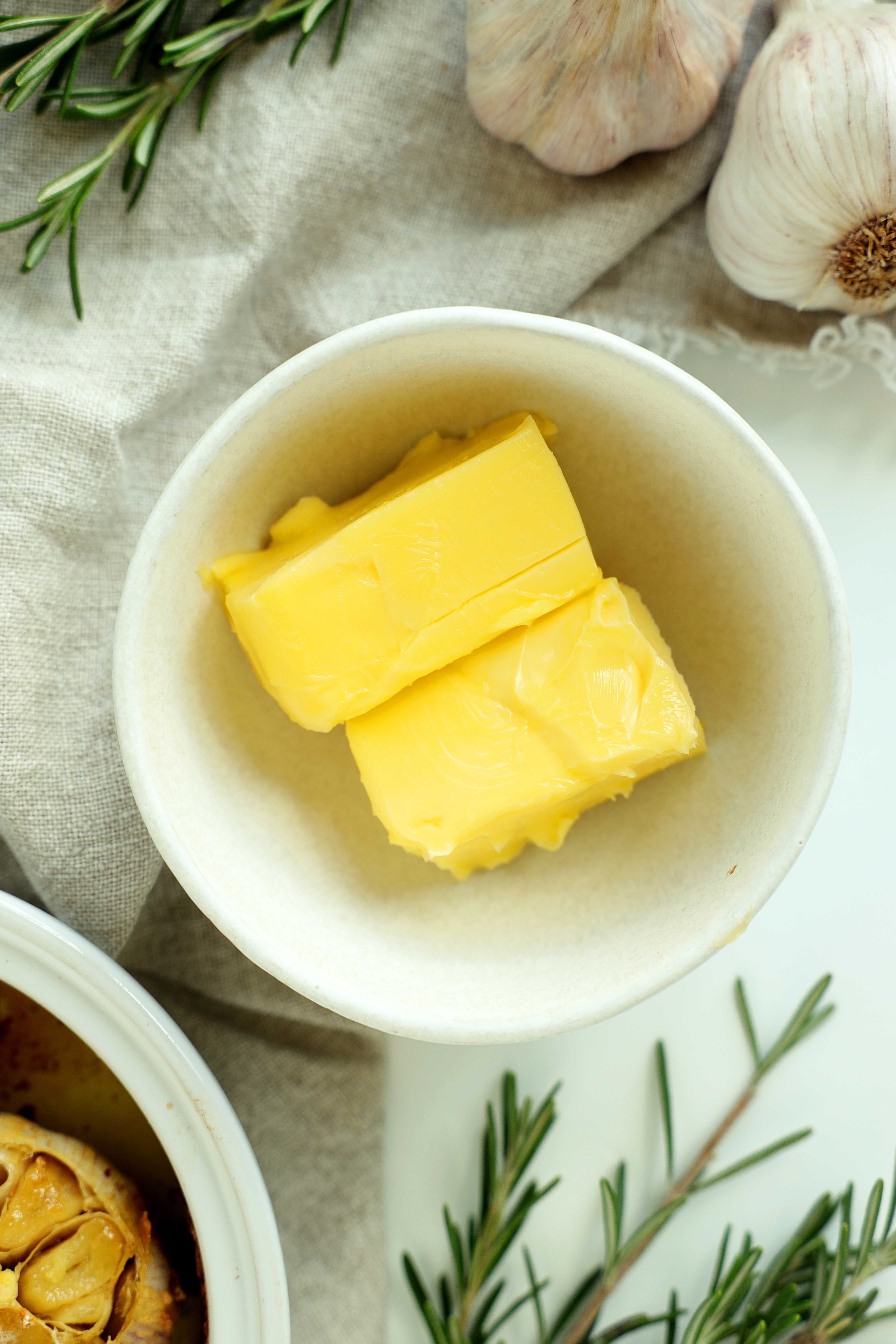 Softened butter in a white mixing bowl ready for roasted garlic and herbs.