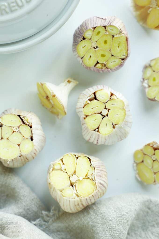 Whole garlic bulbs with their tops cut off, exposing the raw cloves before roasting.